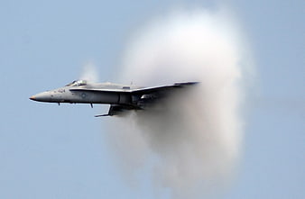 Military fighter jet breaking the sound barrier with vapor cone