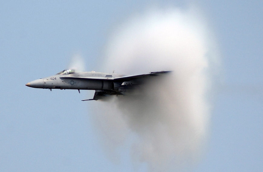 Military fighter jet breaking the sound barrier with vapor cone