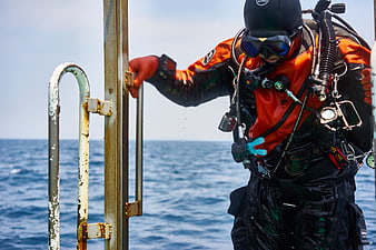 Commercial Diver in Orange Suit Preparing for Ocean Dive