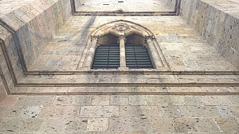 Gothic stone window with iron bars on historic church facade