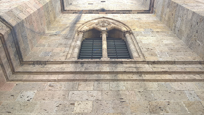 Gothic stone window with iron bars on historic church facade