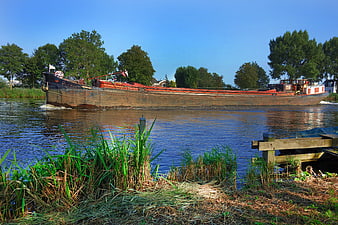 Traditional wooden barge sailing on a calm river