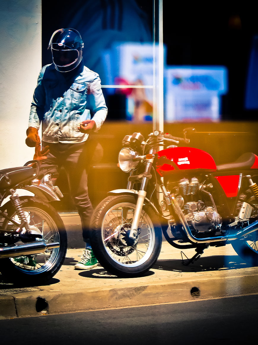 Man in Helmet Standing Next to Red Motorcycle at Night