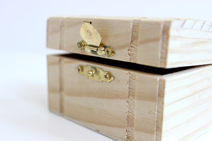 Close-up of wooden box with brass latch on white background