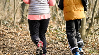 Two runners jogging on a forest path in winter