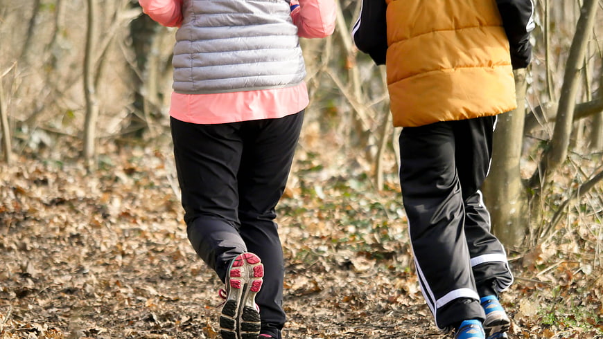 Two runners jogging on a forest path in winter