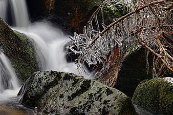 Frozen waterfall with icicles and mossy rocks in winter
