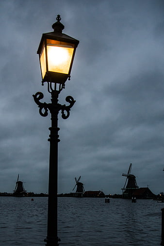 Glowing Street Lantern with Dutch Windmills at Dusk