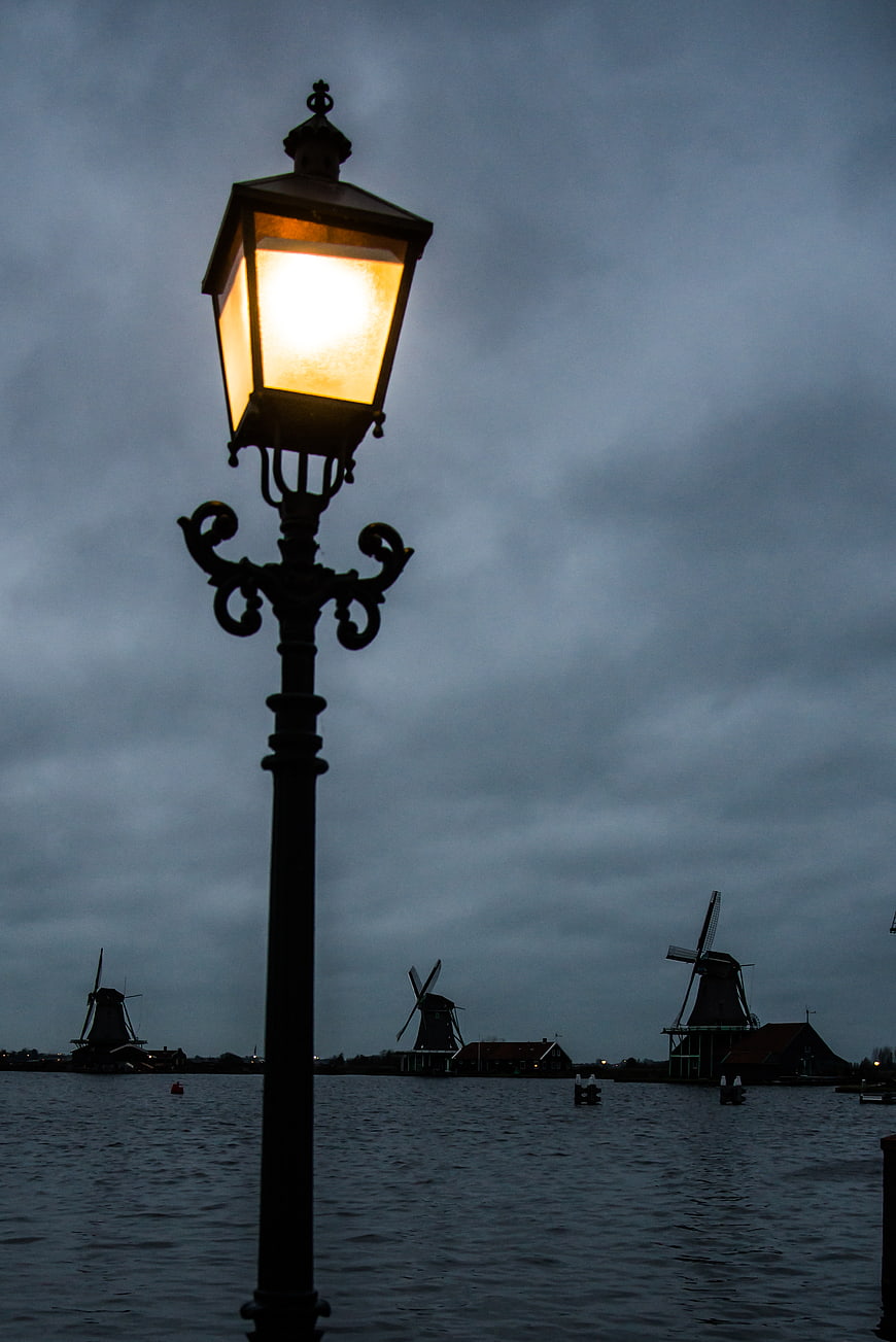 Glowing Street Lantern with Dutch Windmills at Dusk