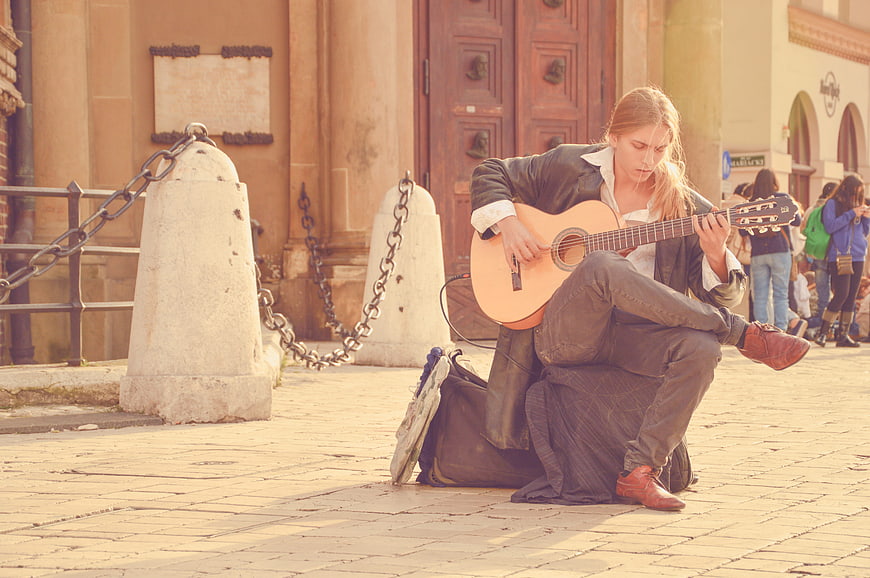 Street musician playing acoustic guitar in European square