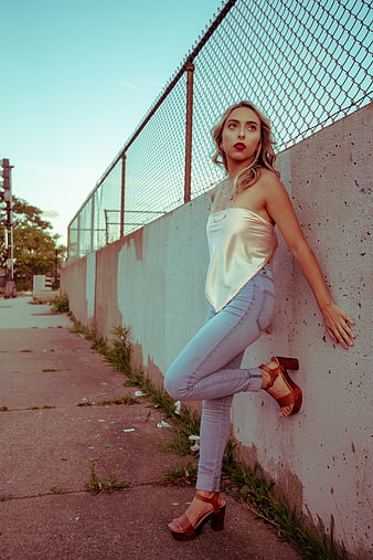 Stylish blonde woman posing against urban concrete wall