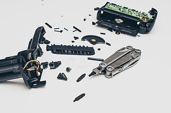 Dismantled electronic device parts and multi-tool on white background