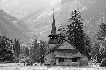 Black and white stone church in mountain valley landscape
