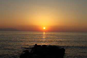 Serene Sunset Over Ocean with Silhouetted Rocks