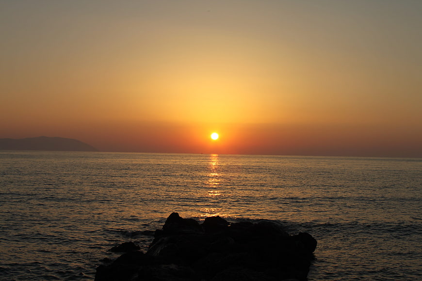 Serene Sunset Over Ocean with Silhouetted Rocks