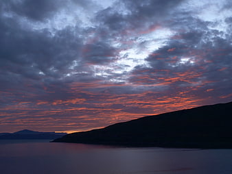 Dramatic Sunset Over Silhouetted Coastline and Ocean