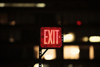 Glowing Red Exit Sign in Dark Industrial Setting