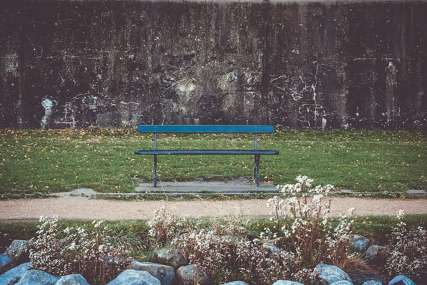 Lonely blue bench in park with textured wall background