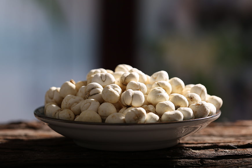 Bowl of Dried Lotus Seeds on Rustic Wooden Table