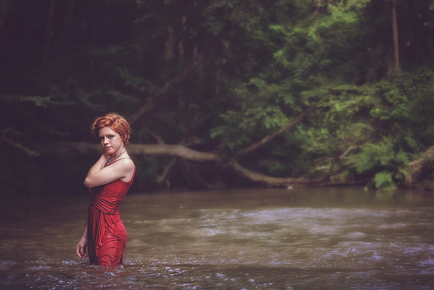 Woman in Red Dress Standing in Forest River