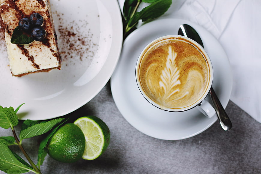 Top view of cappuccino with latte art and slice of cake