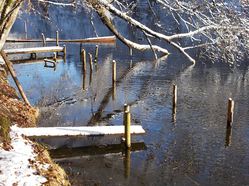 Snowy wooden docks on a calm winter lake with reflections
