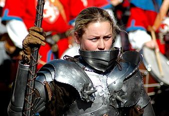 Woman in medieval armor holding a polearm at a historical tournament