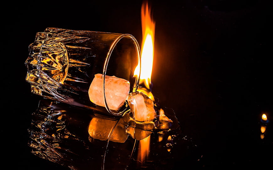 Dramatic Overturned Glass With Burning Ice Cubes On Black Background