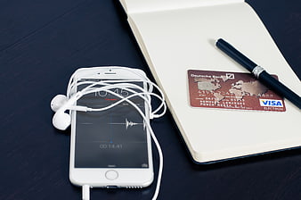 Smartphone with headphones, notebook, and credit card on desk