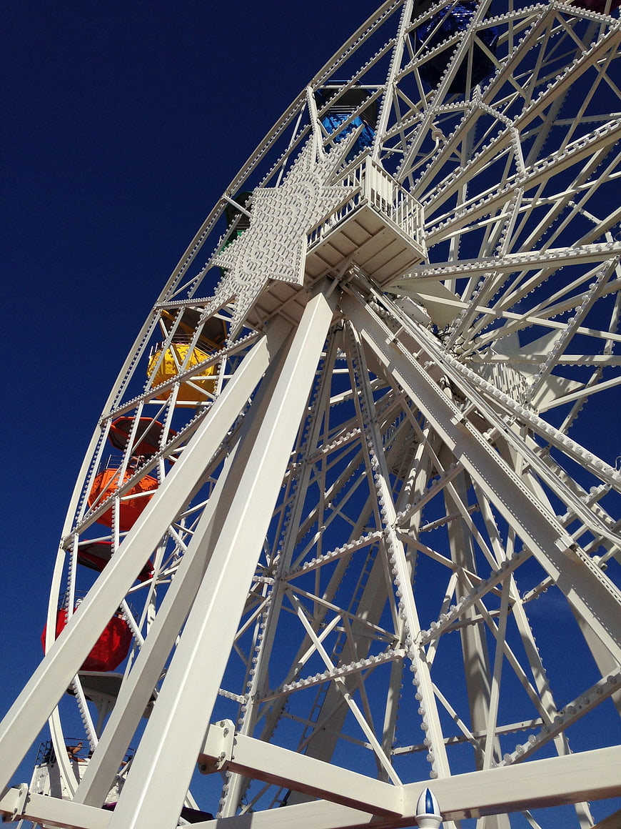 Low angle view of white ferris wheel against blue sky