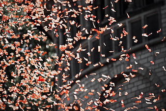 Red and white confetti falling against a dark urban background