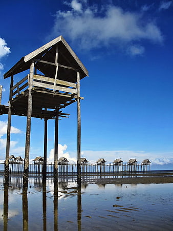Traditional wooden stilt houses on a beach at low tide
