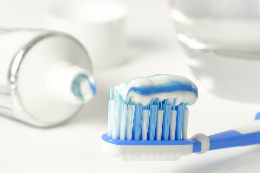 Blue and white toothbrush with toothpaste on bristles