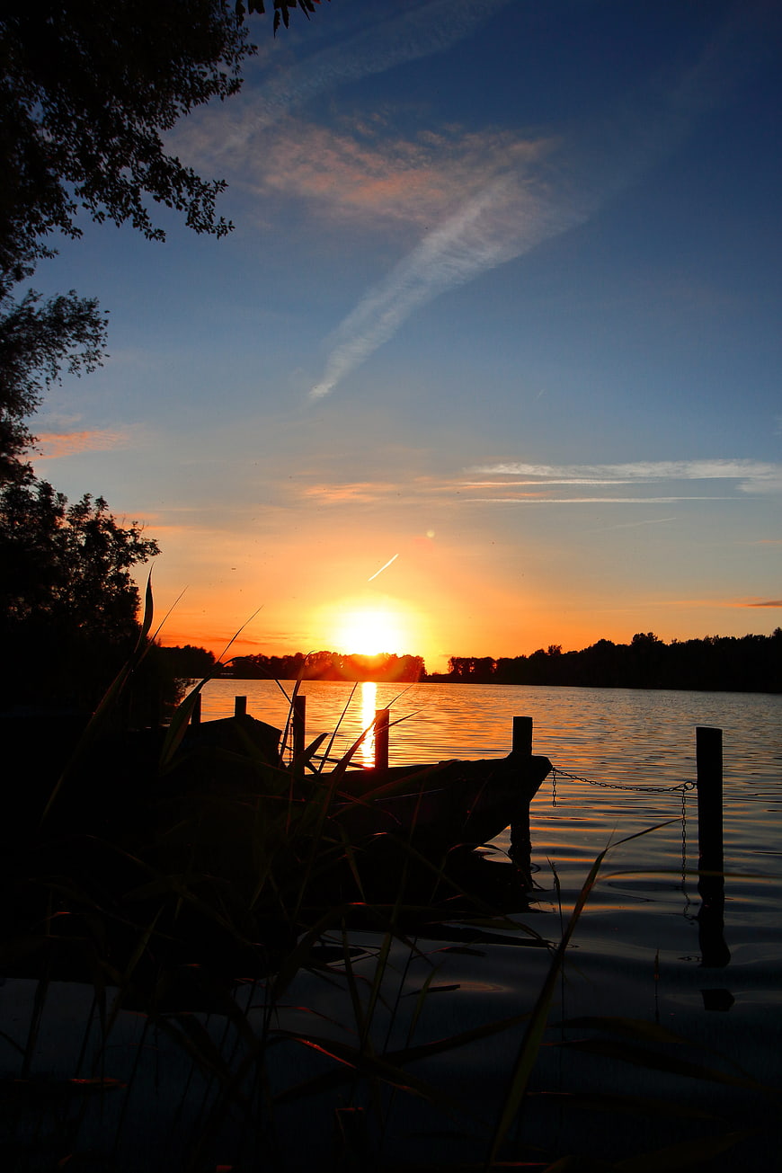 Silhouette of boat at sunset on calm lake