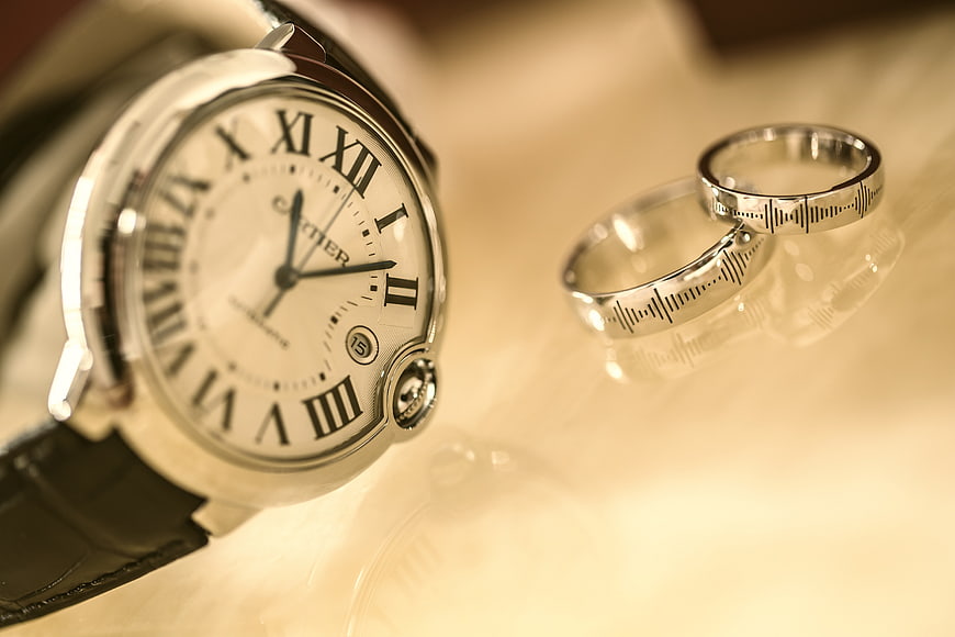 Luxury Cartier Watch and Wedding Rings on Reflective Surface