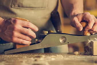 Carpenter Planing Wood with Hand Plane in Workshop