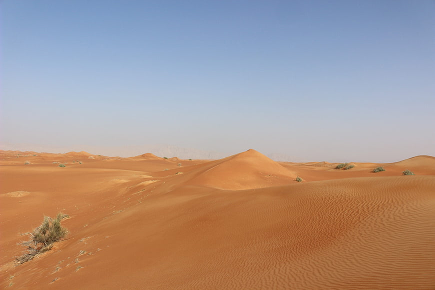 Vast orange sand dunes under clear blue sky