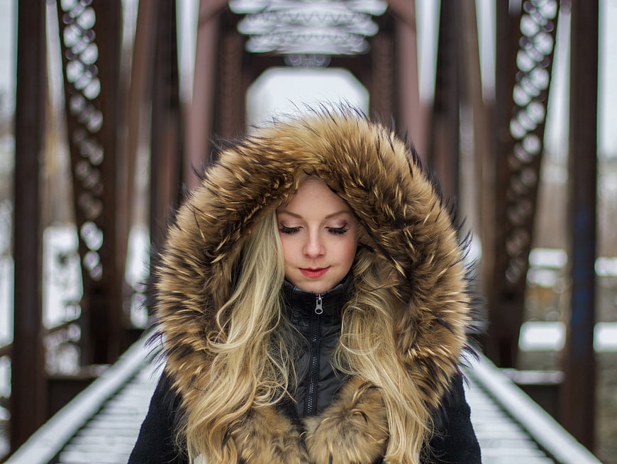 Blonde Woman in Fur Hooded Jacket on Winter Bridge