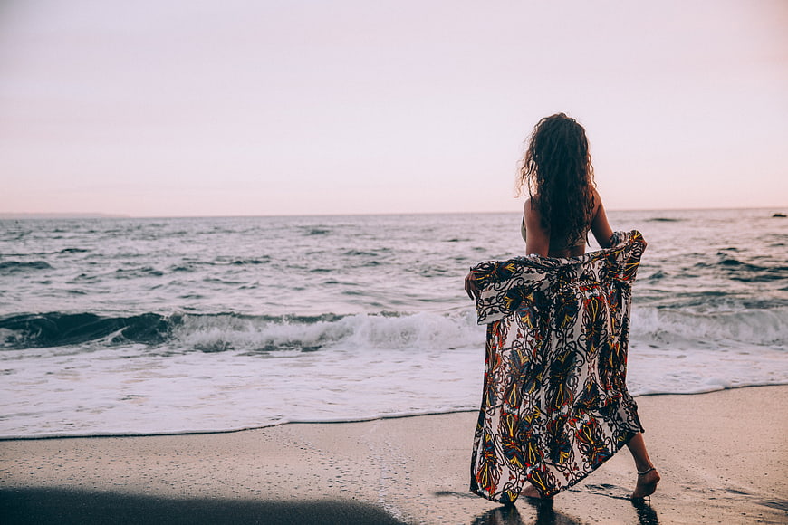 Woman in Patterned Dress Walking on Beach at Sunset