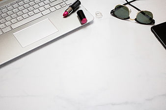 Minimalist Flat Lay of Laptop, Lipstick, and Sunglasses on White Desk