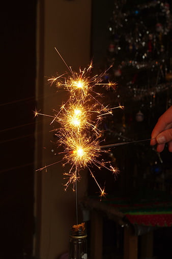 Hand Lighting Sparkler Near Christmas Tree