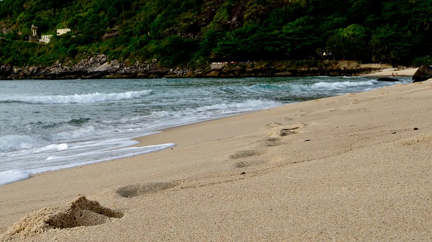 Footprints in sand on tropical beach with ocean waves