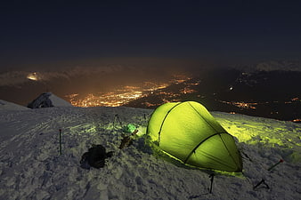 Glowing Green Tent on Snowy Mountain Peak at Night