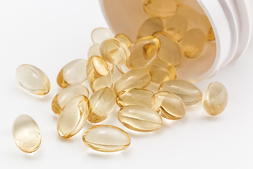 Spilled Golden Fish Oil Softgel Capsules from White Bottle