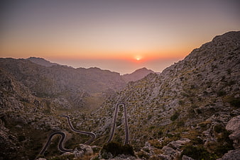 Winding Mountain Road at Sunset with Golden Sky