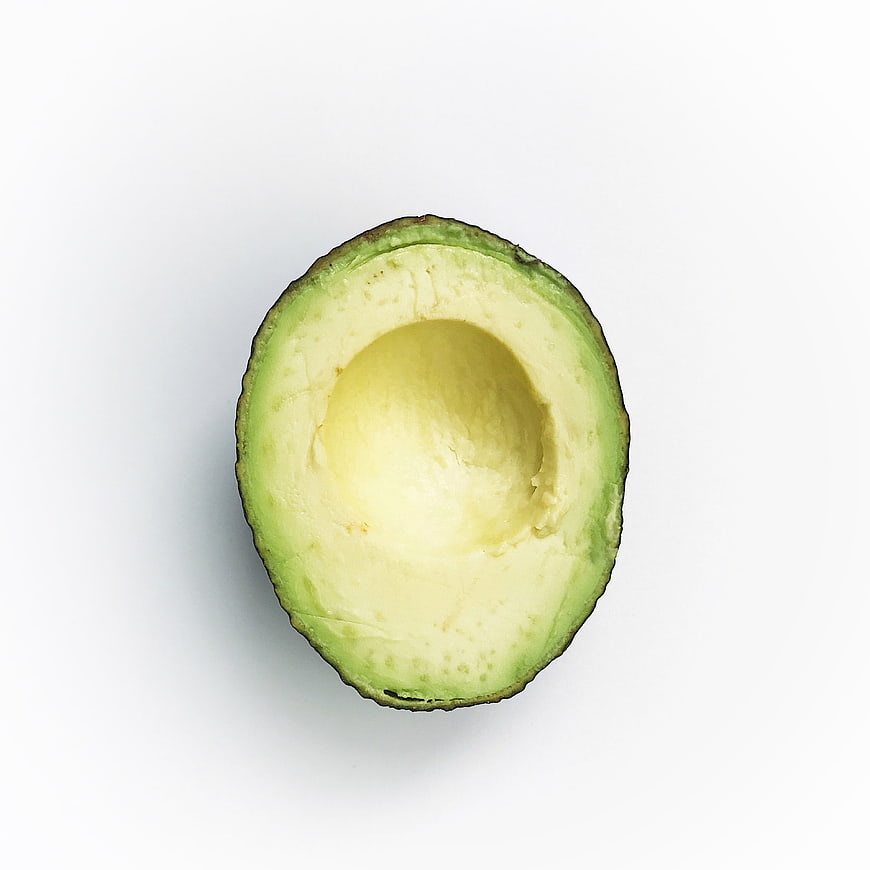 Half avocado with pit removed on white background