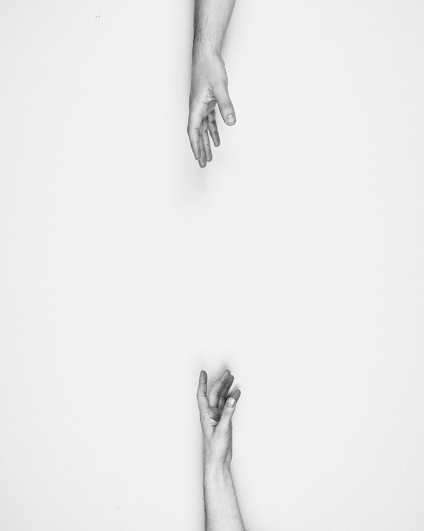 Black and white hands reaching towards each other with distance