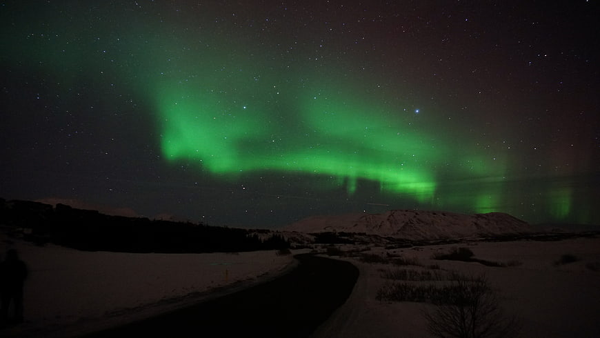 Green Aurora Borealis Over Snowy Winter Road at Night
