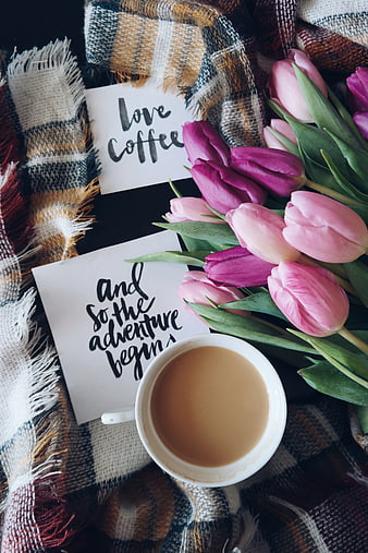 Flat lay of coffee cup, pink tulips, and handwritten quotes on plaid blanket