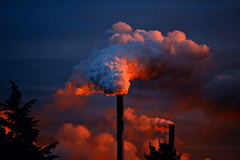 Industrial Factory Smokestacks Emitting Smoke Against Dramatic Sunset Sky